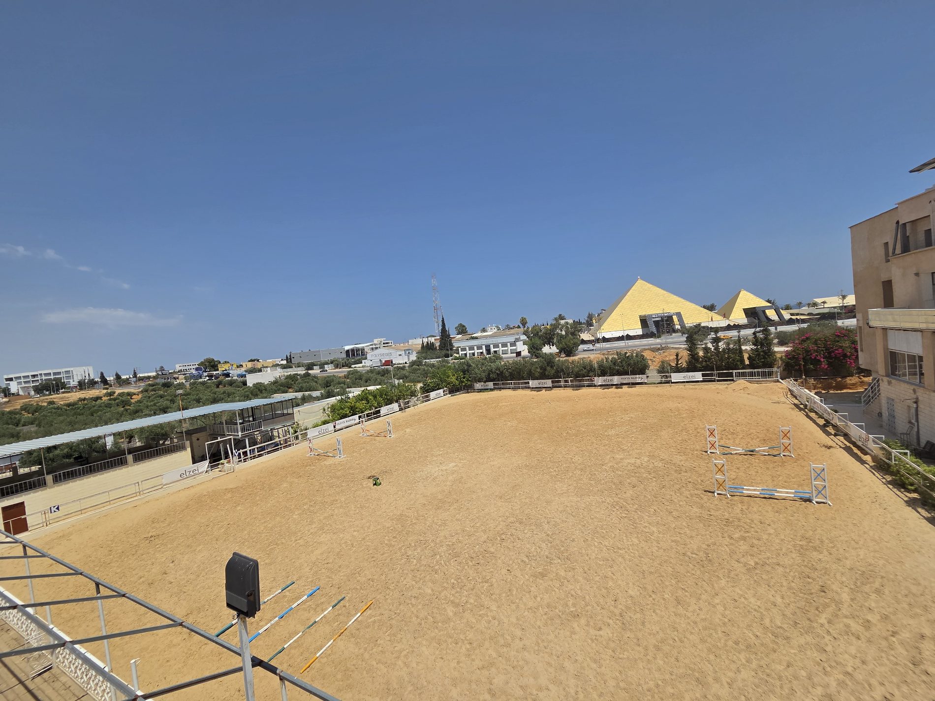 The full sand arena with jumps set, the Pyramids hall beyond