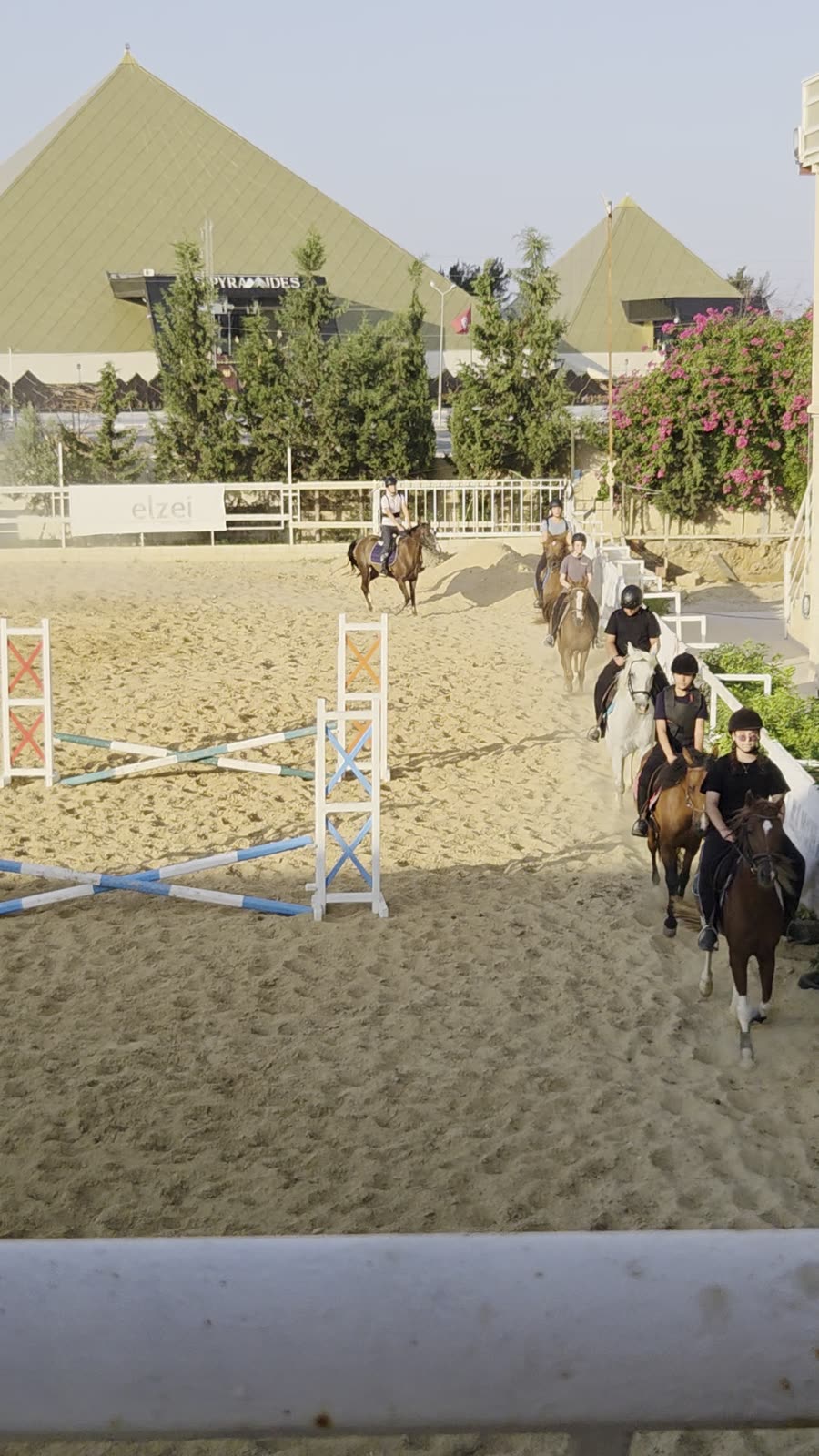 Riders in the sand arena at golden hour